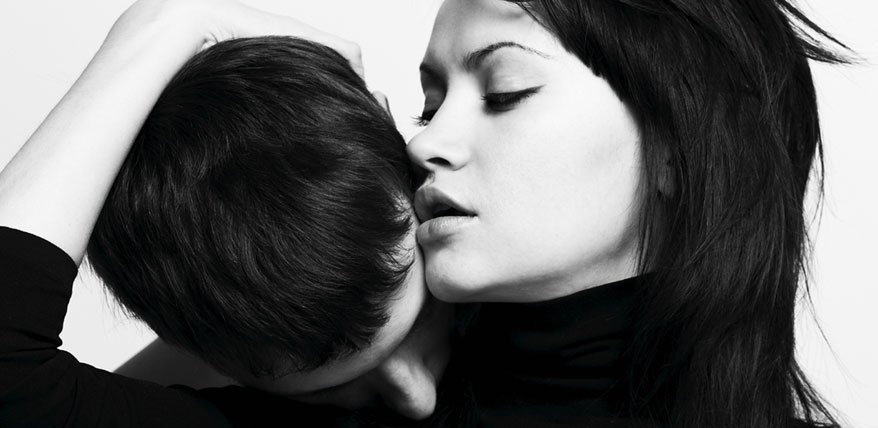 Mann küsst einer Frau den Nacken.