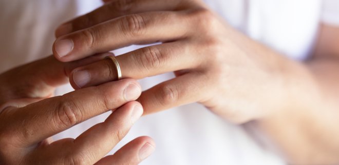 Verliebt in einen verheirateten Mann: Mann schiebt Ehering von seinem Finger.