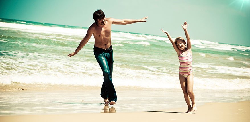 Vater und Tochter spielen am Strand.