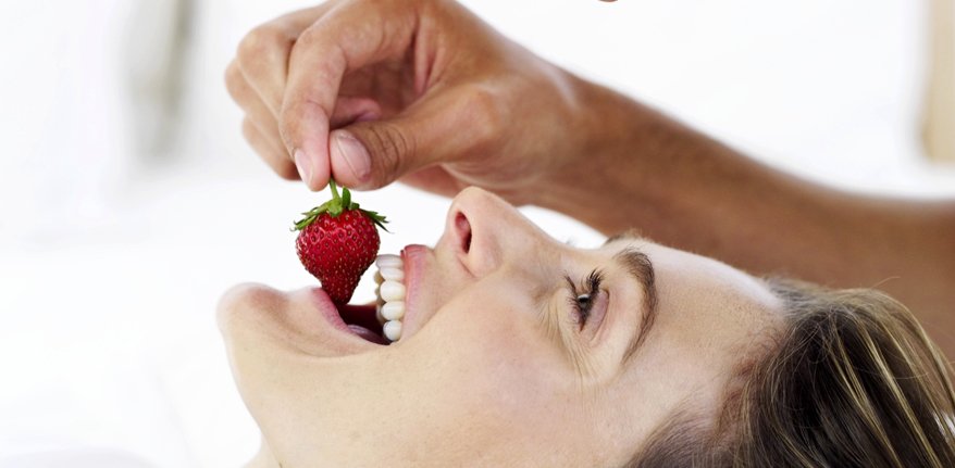 Eine Frau beisst in eine Erdbeere.