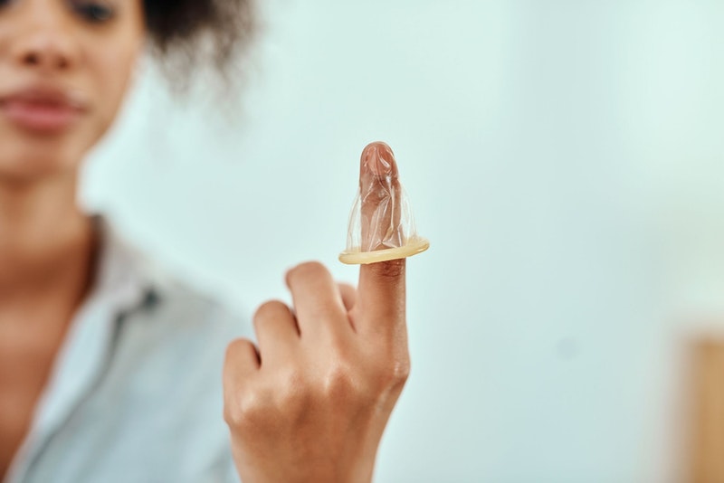 Eine Frau hat ein Kondom über den Finger gestülpt.