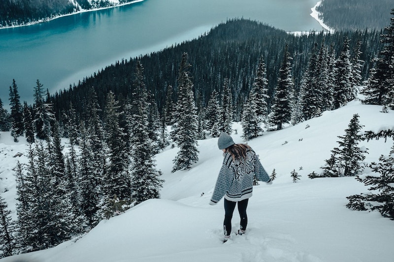 Eine Frau steht in winterlicher Landschaft mit See und Schnee
