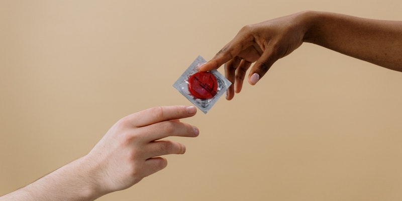 Eine Hand reicht einer anderen ein Kondom