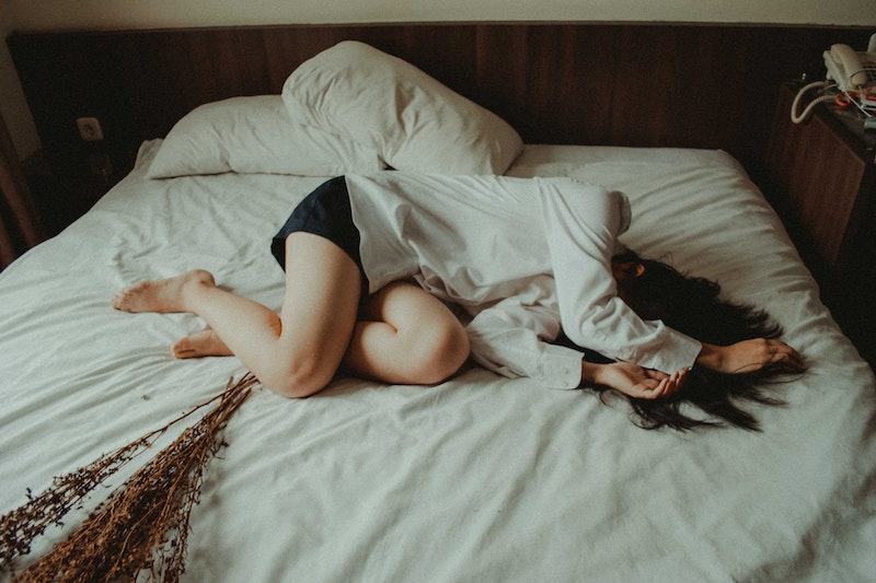 Eine Frau liegt im Bett und hält ihre Arme über den Kopf.