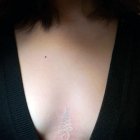 Weisses Tattoo zwischen der Brust