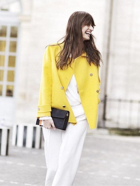 Die französische Stilikone Caroline de Maigret bringt ihr All-White-Outfit mit gelber Jacke zum Strahlen.