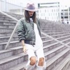 Fashion-Bloggerin Alex mixed oversized Shirt mit Bomberjacke, weisser Jeans und Hut.