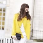 Die französische Stilikone Caroline de Maigret bringt ihr All-White-Outfit mit gelber Jacke zum Strahlen.