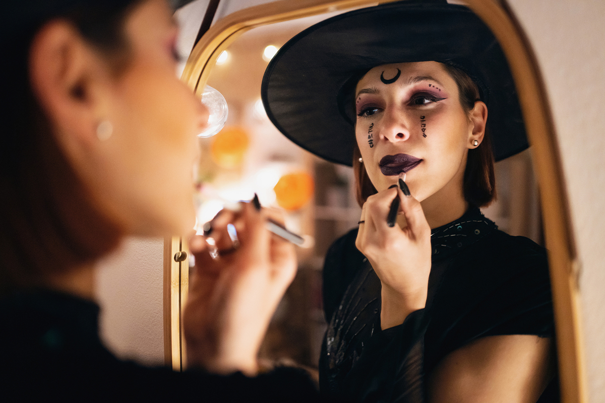 Eine Frau macht sich bereit für Halloween und schminkt sich vor dem Spiegel.