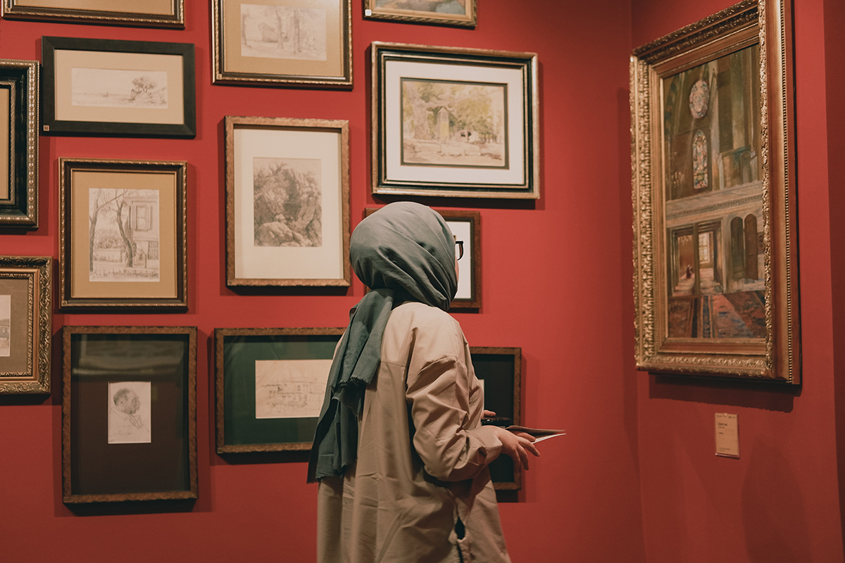 Eine Frau steht im Museum und betrachtet die Gemälde.