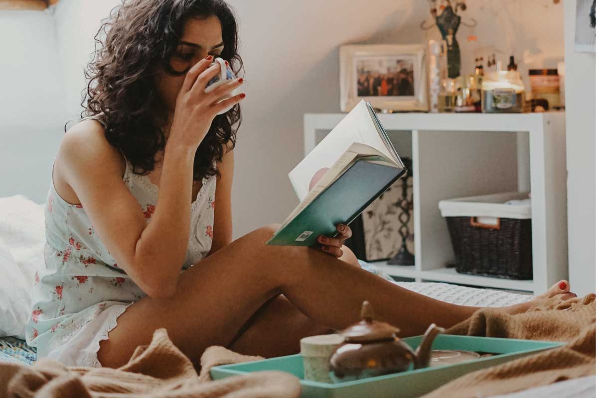 Selfcare, gemütlich im Bett mit einer Tasse Tee und einem Buch ist ein guter, persönlicher Neujahrsvorsatz.