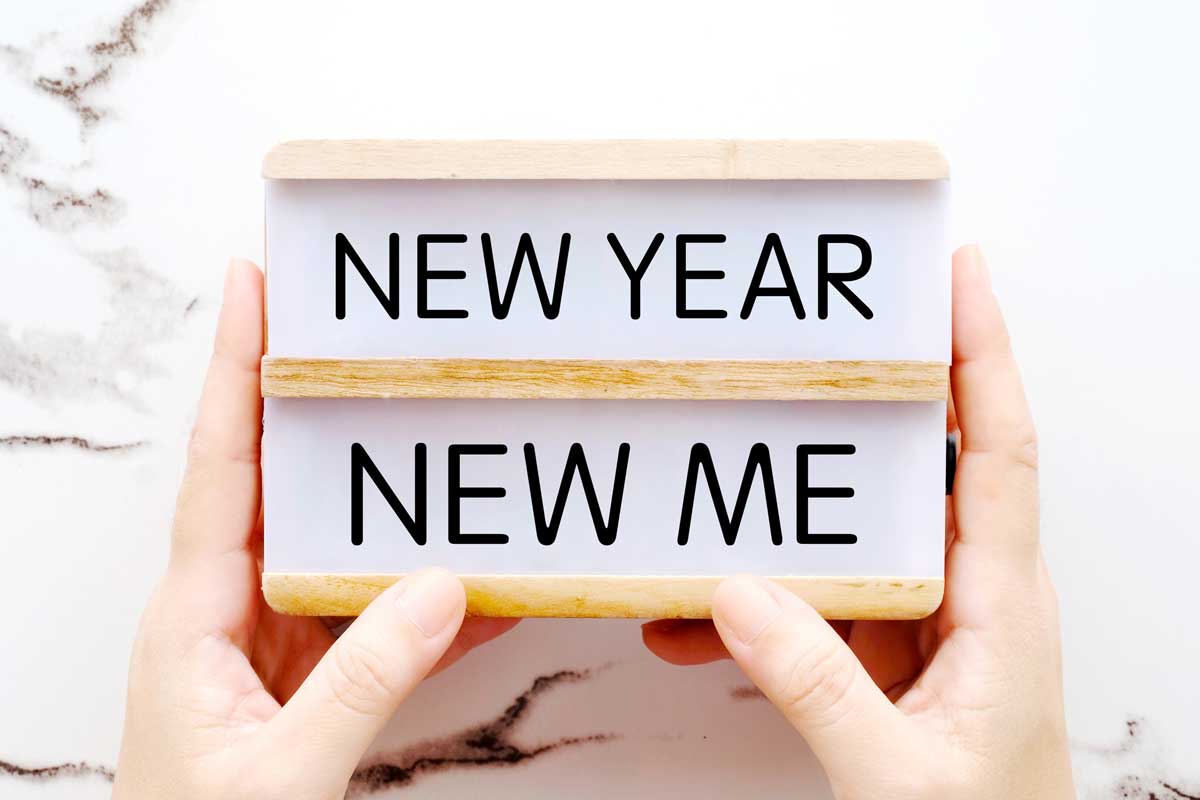 Ein Schild in den Händen auf dem steht «New Year, New Me»