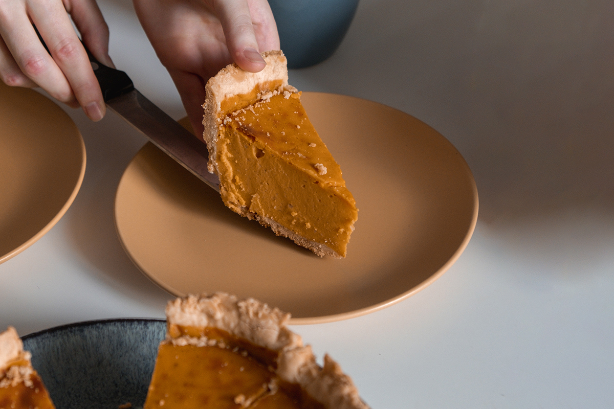 Ein Stück Pumpkin Pie wird auf einen Teller gelegt.