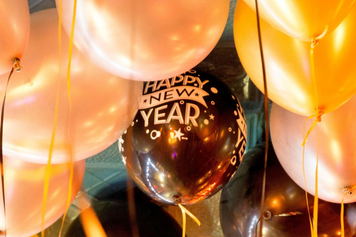 Goldene und weisse Ballons mit einem schwarzen «Happy New Year»-Ballon in der Mitte.