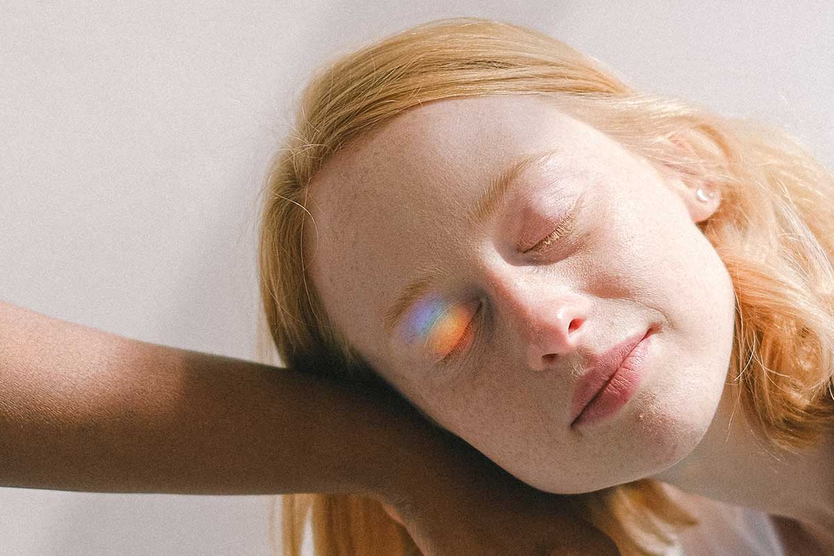 Eine Frau benutzt eine Tageslichtlampe und hat einen Regenbogen farbigen Licht Reflex auf dem Auge.