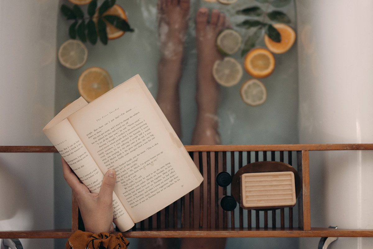 Eine Frau sitzt in der Badewanne und liest ein Buch.